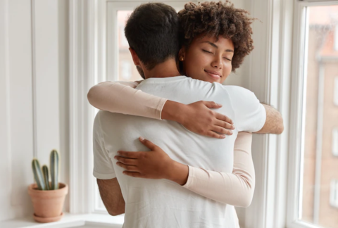 mulher negra abraçando um homem simulando o perdão.